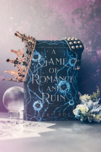 Image of the book standing up with a crown hanging off it a glass orb next to it with flowers